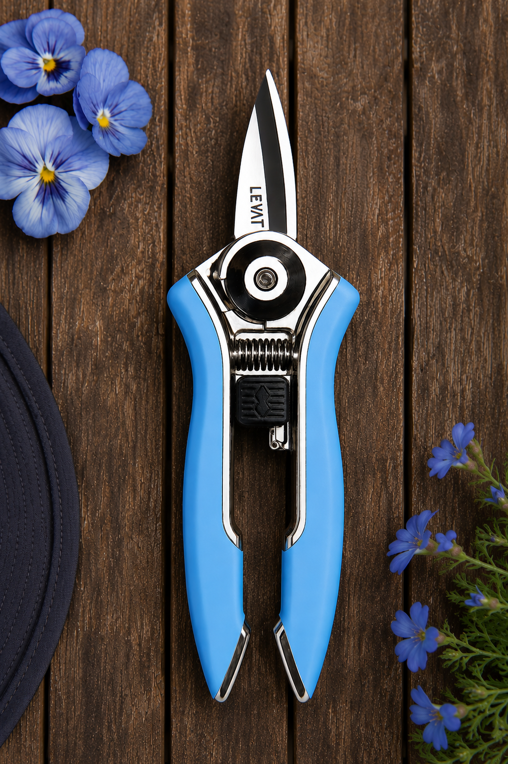 A pair of LEWT pruning shears with bright blue handles and silver metal blades, displayed on a dark brown wooden background with decorative blue flowers.