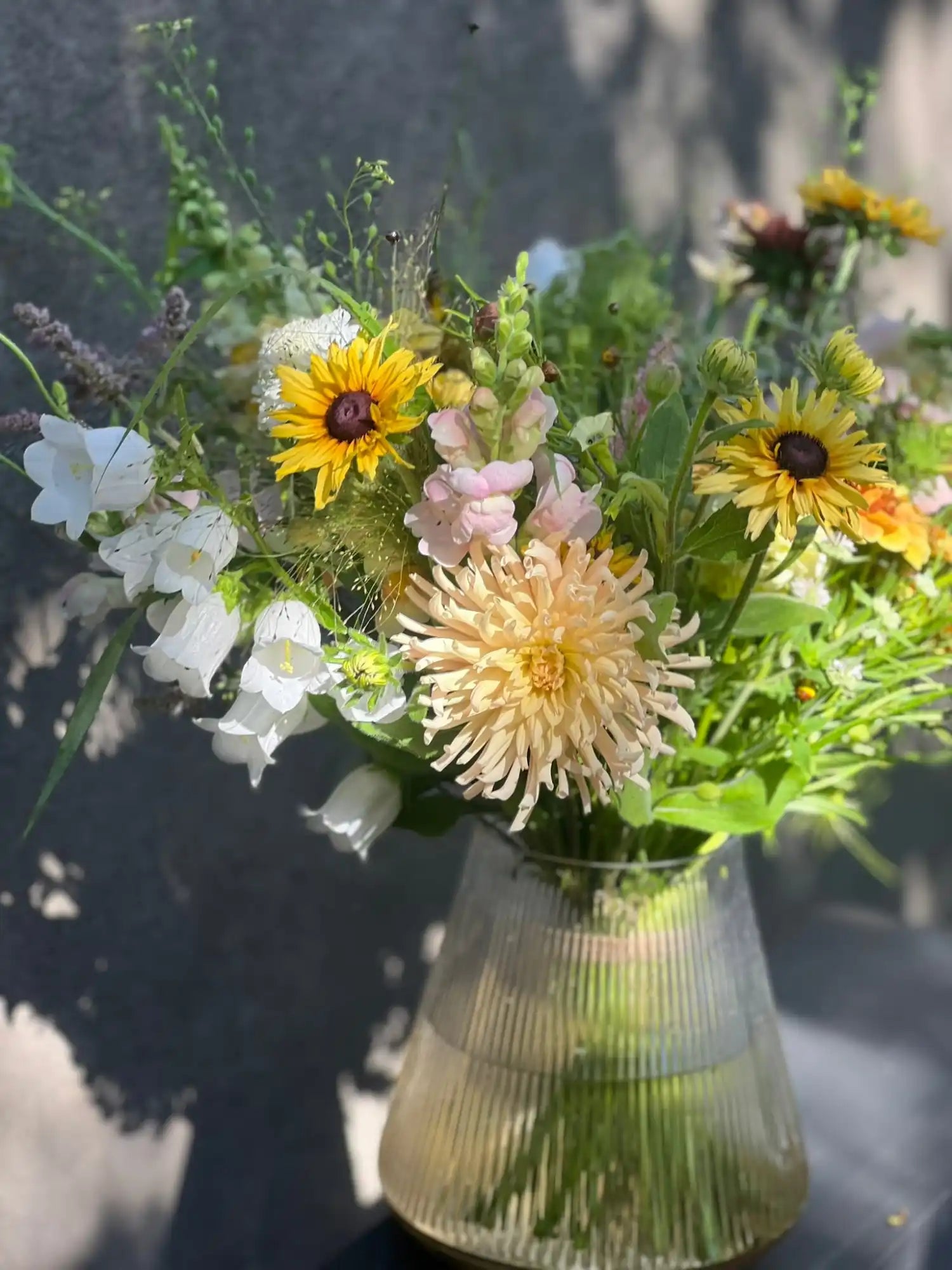 A vibrant arrangement of fresh-cut flowers in a clear, fluted glass vase.